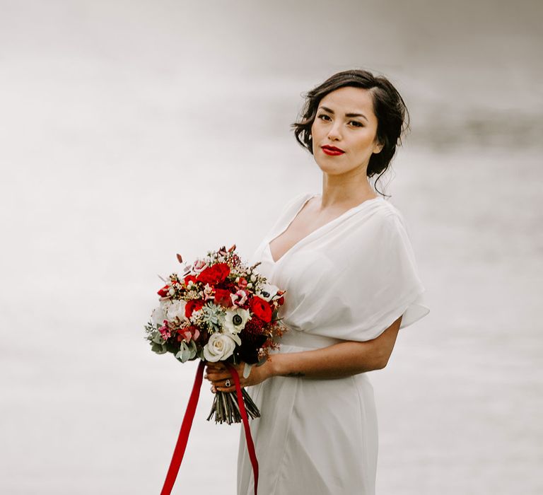 Beautiful bride with wedding hair updo with flowers holding eucalyptus foliage bouquet