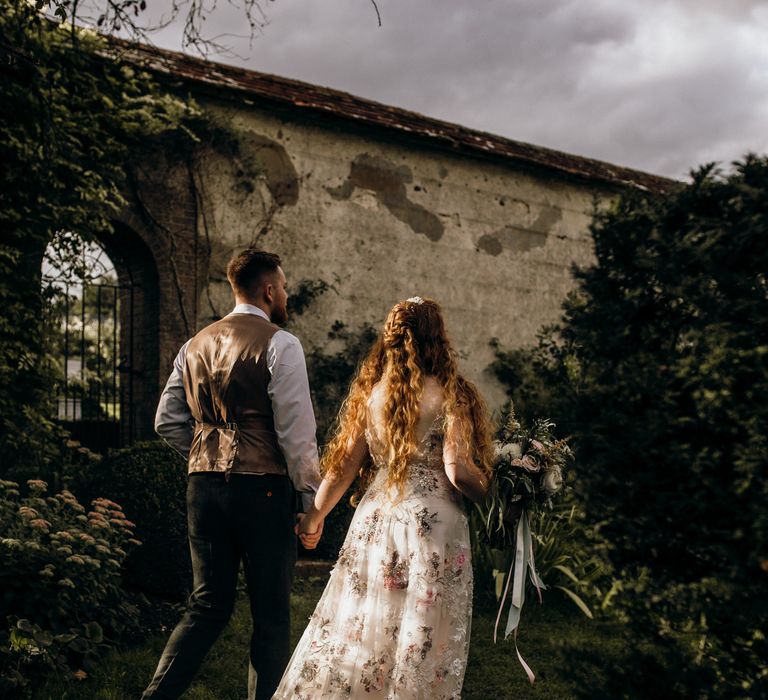 Bride & groom walking through Houghton Lodge Gardens 