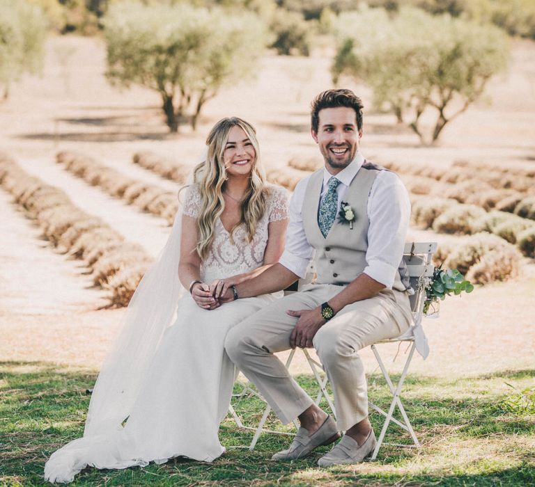 The bride and groom sit in front of lavender fields