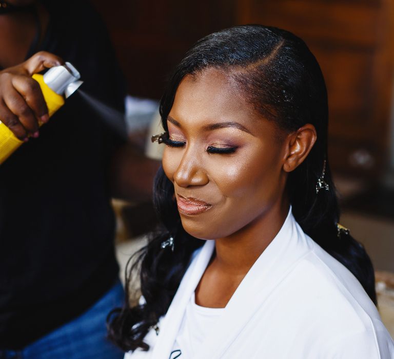 Wedding hairstyles for Black brides. A bride gets her hair curled ready for her wedding.