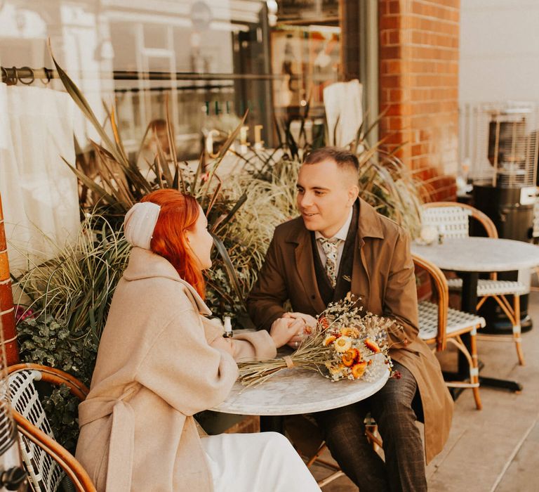 Bride and groom holding hands at London outdoor cafe for city elopement