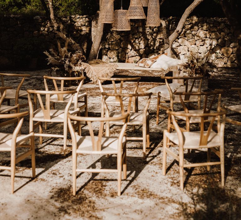 Wooden chairs with wicker lampshades in outdoor ceremony setup