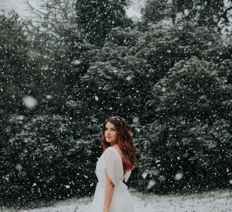 Bride in white dress holding artisan dried flower bouquet at snowy wedding