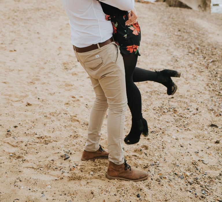 Groom-to-be in a white shirt, chino's and dessert boots picking his Fiancee up during their engagement session 