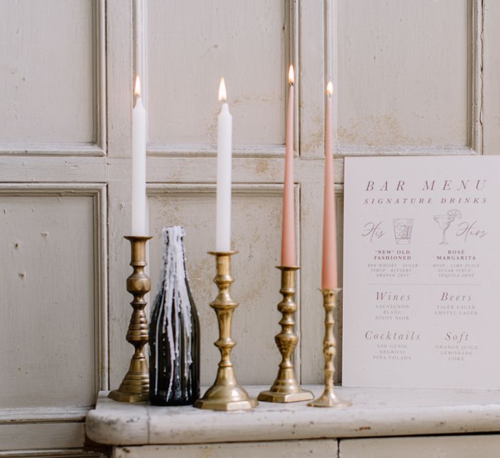 Wedding drinks menu on shelf next to tapered candles. Photography by Rebecca Goddard Photography.