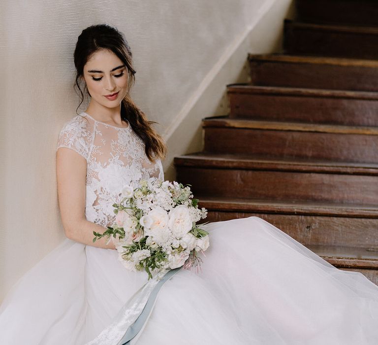 Bride sitting on the stairs at Chateau de la Ruche