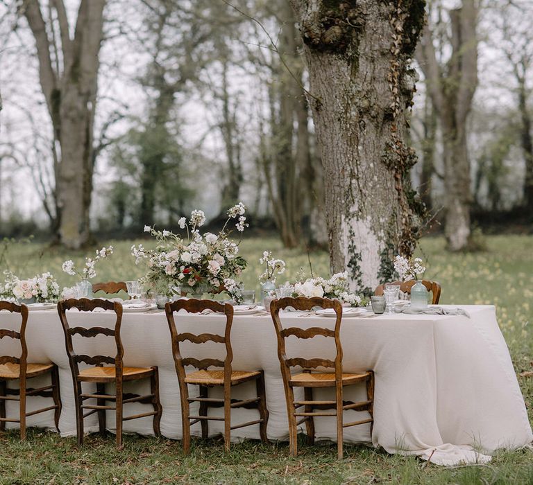 An outdoor woodland table setting in the meadows at Chateau de la Ruche