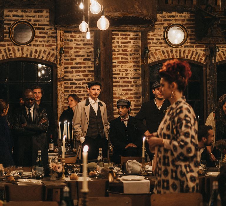 Wedding guests in Peaky Blinder suits at candle lit reception 