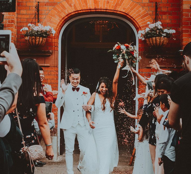 Bride & groom leave ceremony whilst wedding guests throw confetti 