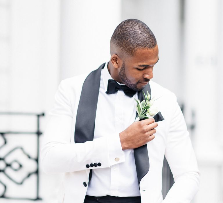 Groom checks floral buttonhole on Monochrome tux