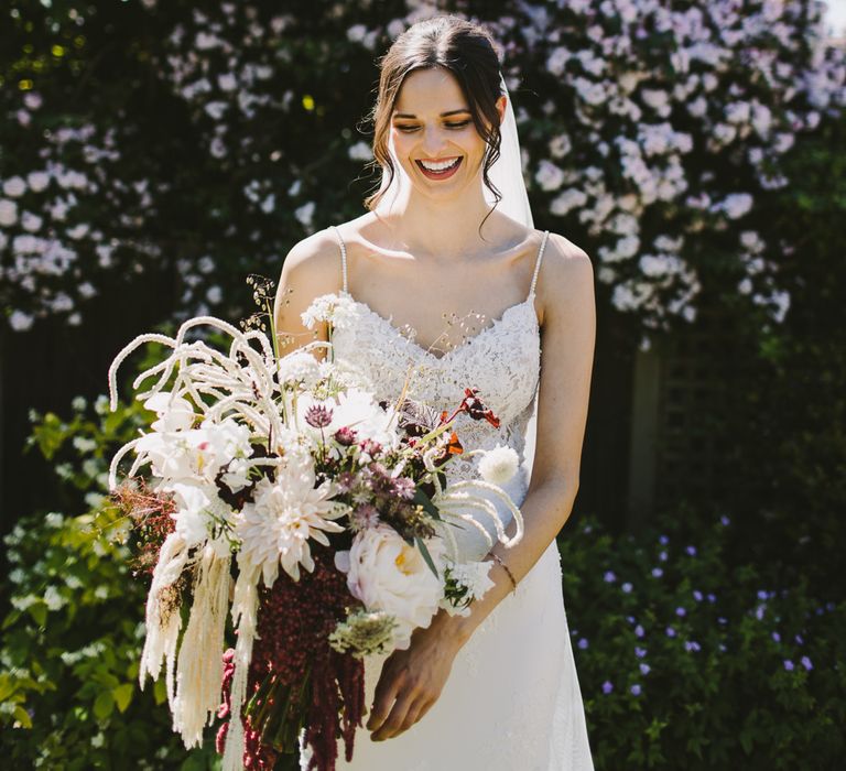 Dark haired bride carries white and dark blooms in floral bouquet