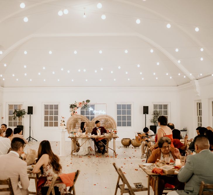 Intimate wedding reception at Core Clapton with bride and groom sitting on Peacock chairs at their sweetheart table