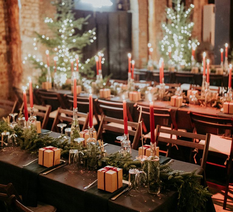 Banquet tables with tapered candles, bottles filled with water and eucalyptus and brown wedding favour boxes