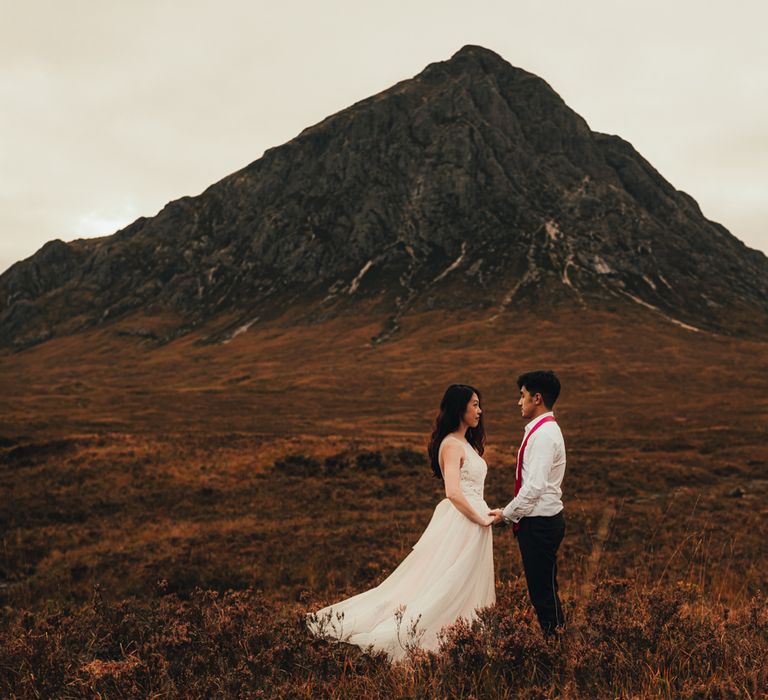 Couple stand within the countryside with mountain in the background