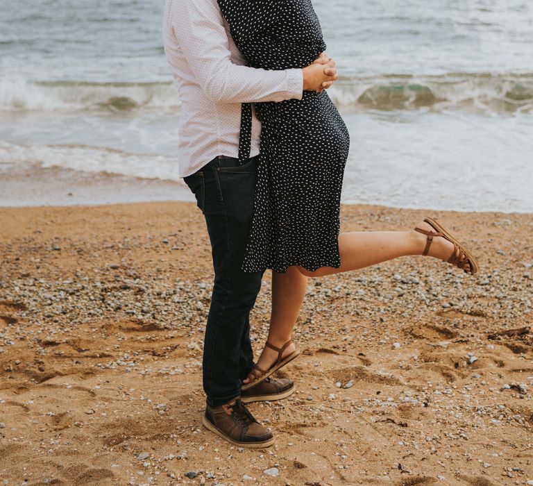 Groom to be holding his wife on the beach for engagement photoshoot