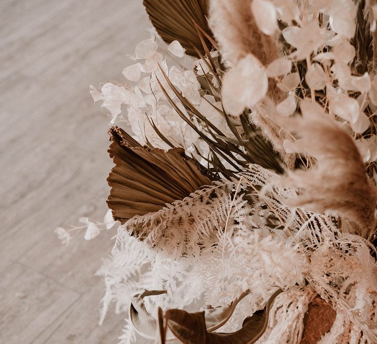 Dried pampas grass, palm leaves, strelitzia leaves and dahlias floral arrangement in a basket 