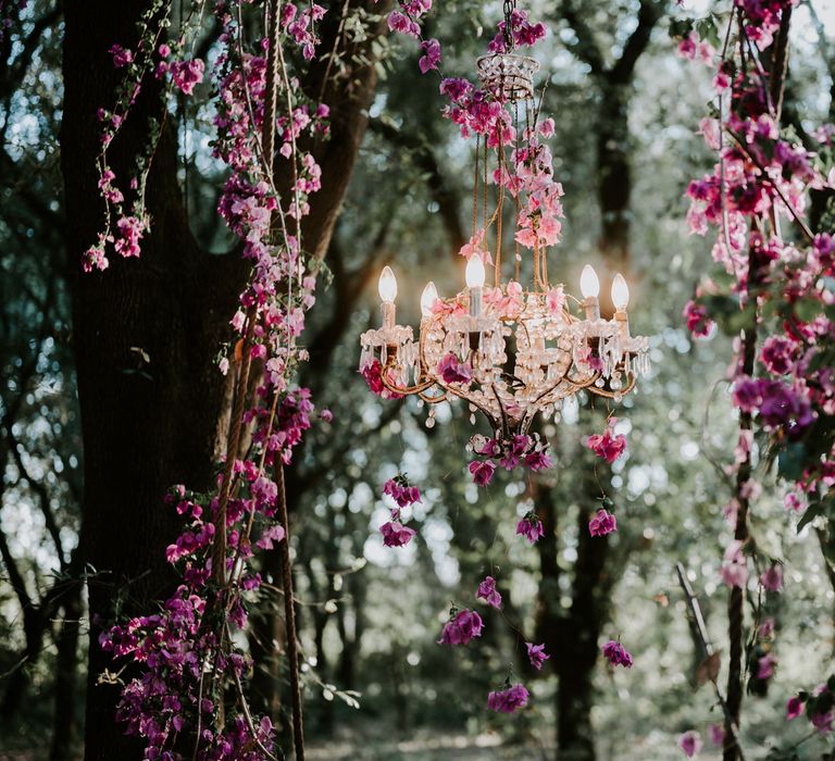 Outdoor droplet chandelier hanging from tree in enchanted forest wedding with pink floral decor