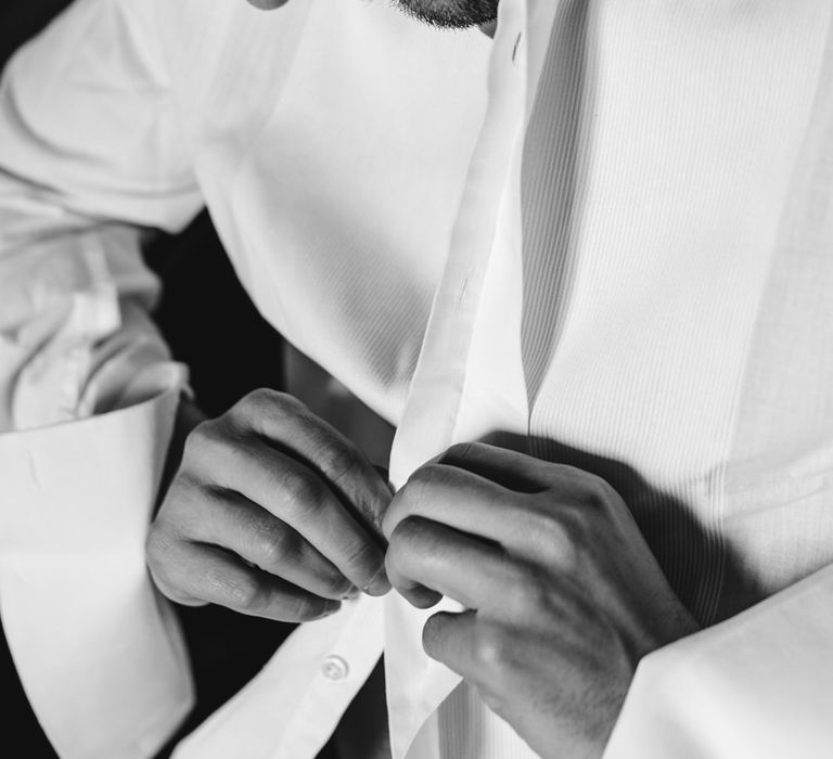 Groom buttoning his shirt