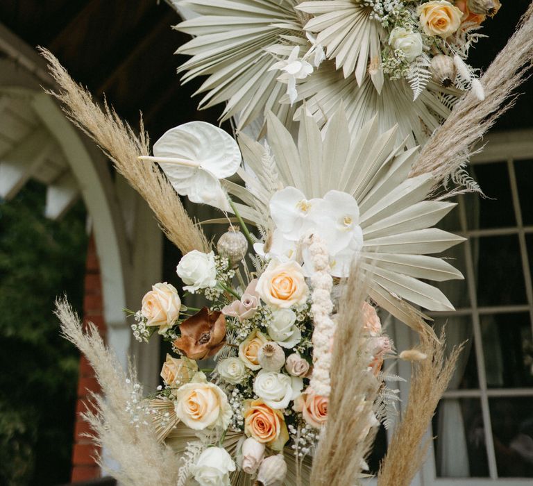 Boho floral archway of dried palms, pampas grass, white anthuriums, roses and orchids at Berwick Lodge