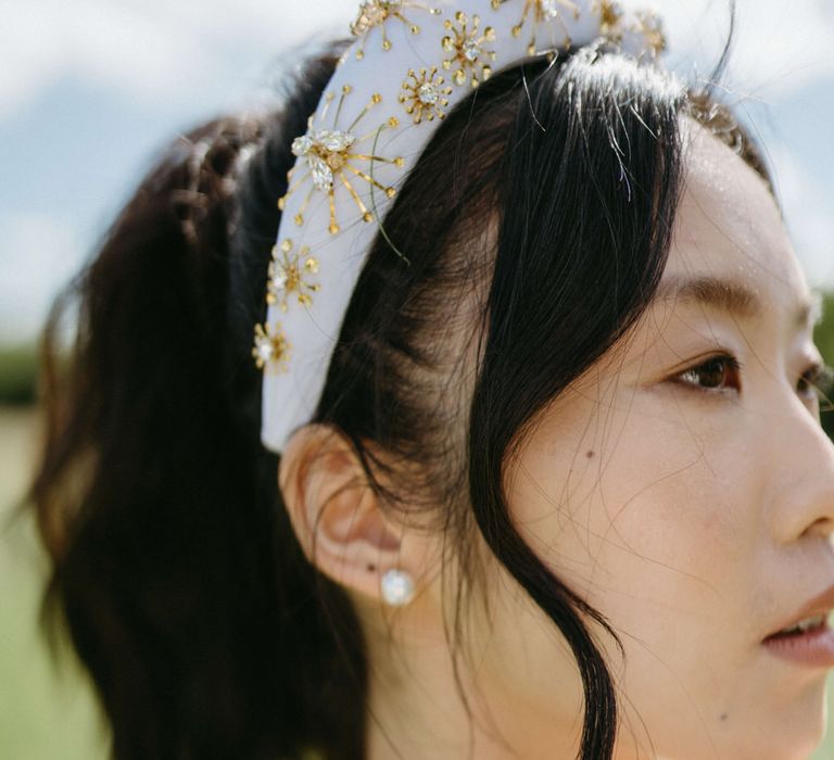 Simple pearl earrings and a white and gold beaded headband for boho bridal style at Berwick Lodge