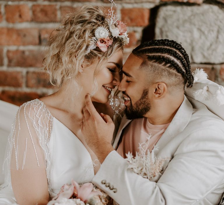 Bride and groom together on a hammock, the bride has tropical pink shells and florals as a headband