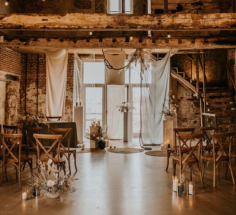 Godwick Great Hall and Barn wedding ceremony with drapes, festoon lights, wicker rugs and white flowers 