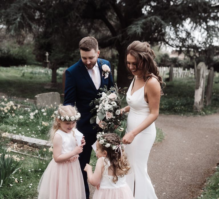 Bride and groom with two small flower girls wearing pink dresses and flower crowns