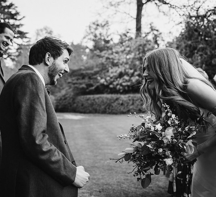 Black and white portrait of the bride and grooms reaction to seeing each other at the altar at their outdoor wedding ceremony 