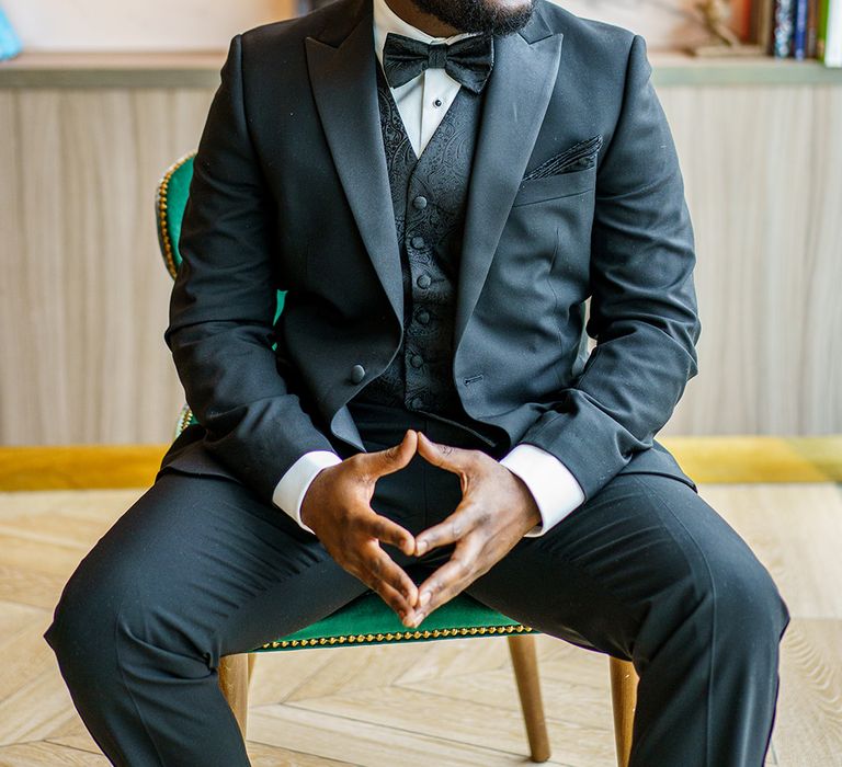 Groom looks to the side whilst wearing black tie and printed waistcoat with matching pocket square 