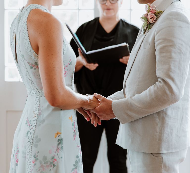 Bride & groom hold hands on the day of their wedding as bride wears pale blue wedding gown