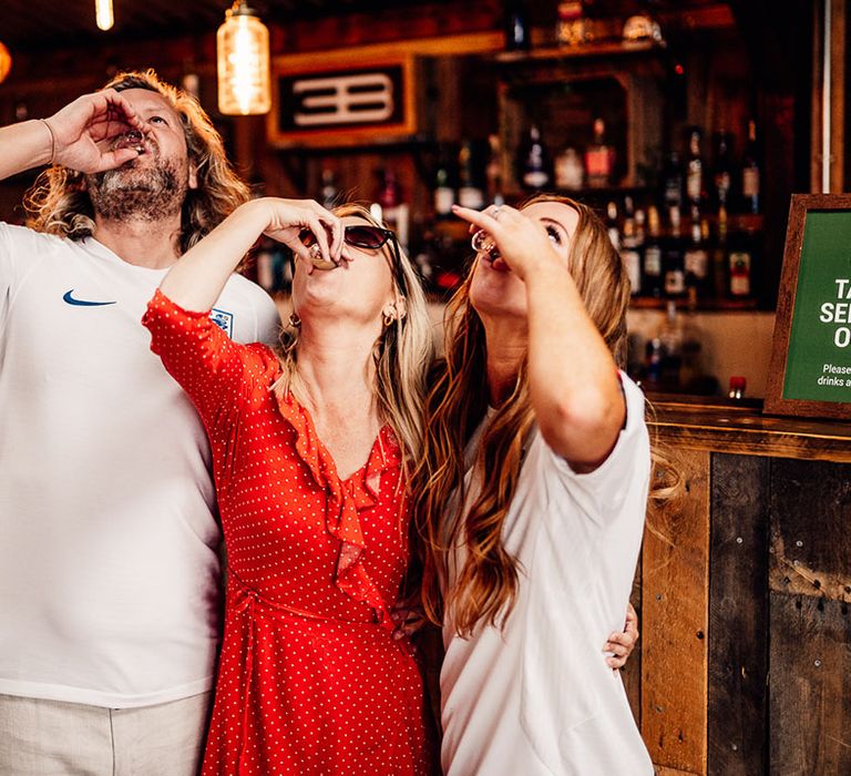 Bride and groom in football shirts do shots with guests