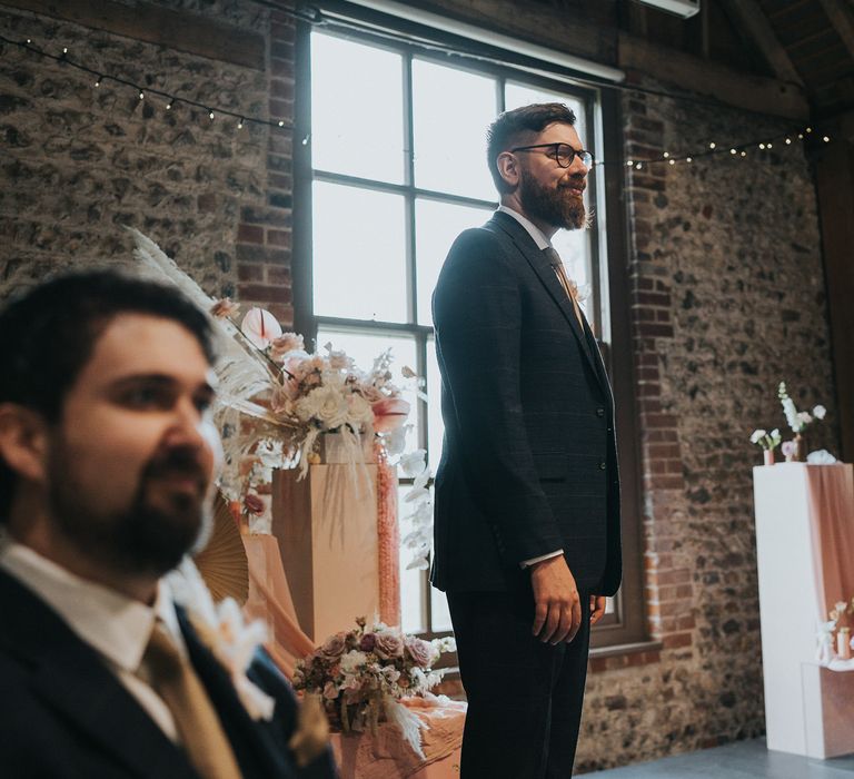 Groom awaits his bride at the end of the aisle on his wedding day