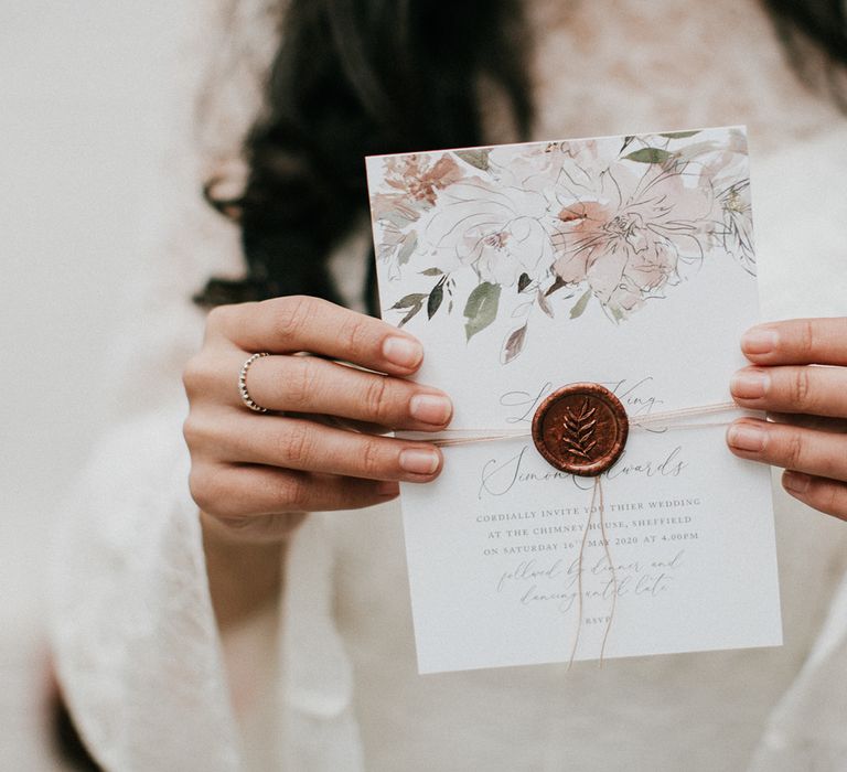 Elegant wedding invitation with pink floral design and gold wax seal 