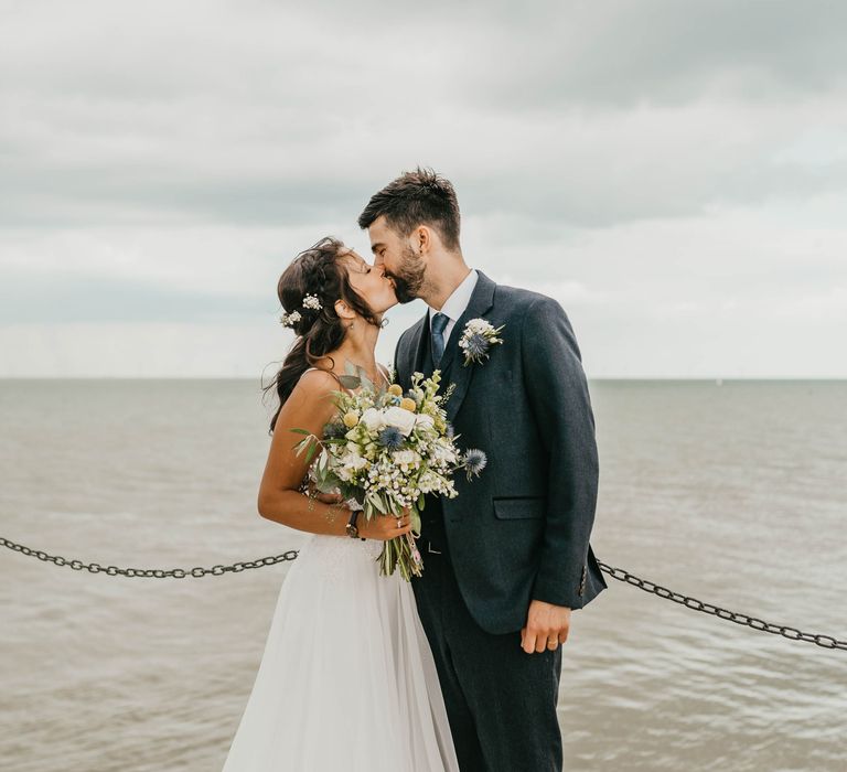 Bride & groom kiss on the beach at Whitstable on their wedding day