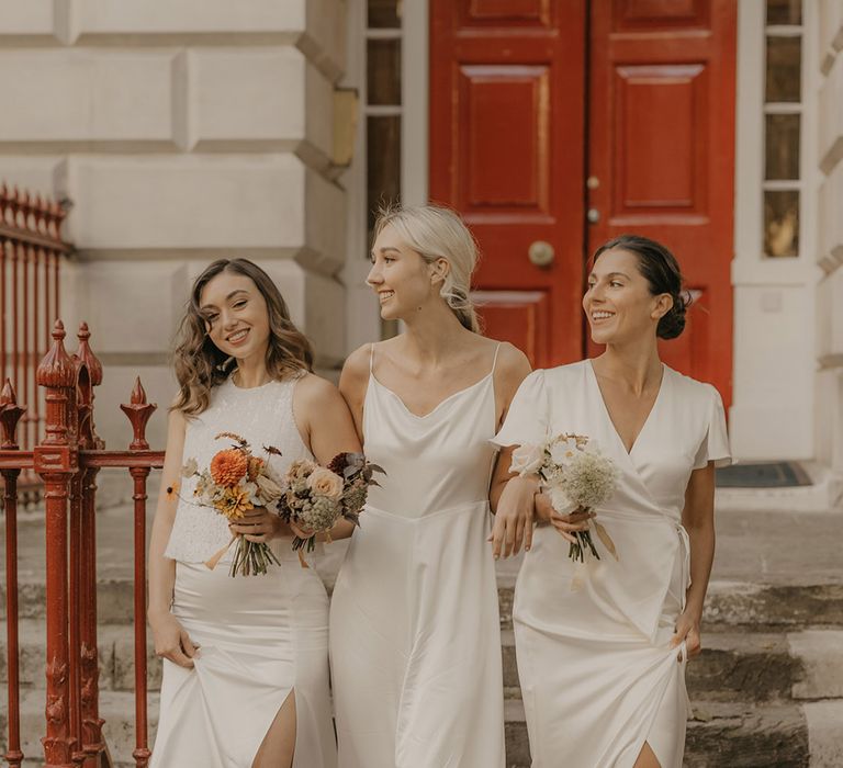 Bridesmaids in a white satin jumpsuit, wrap dress and separates by Constellation Ame walking down the steps at Clerkenwell House 