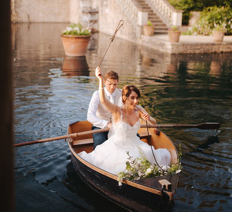 Bride & groom sit with one another in wooden boat at Euridge Manor