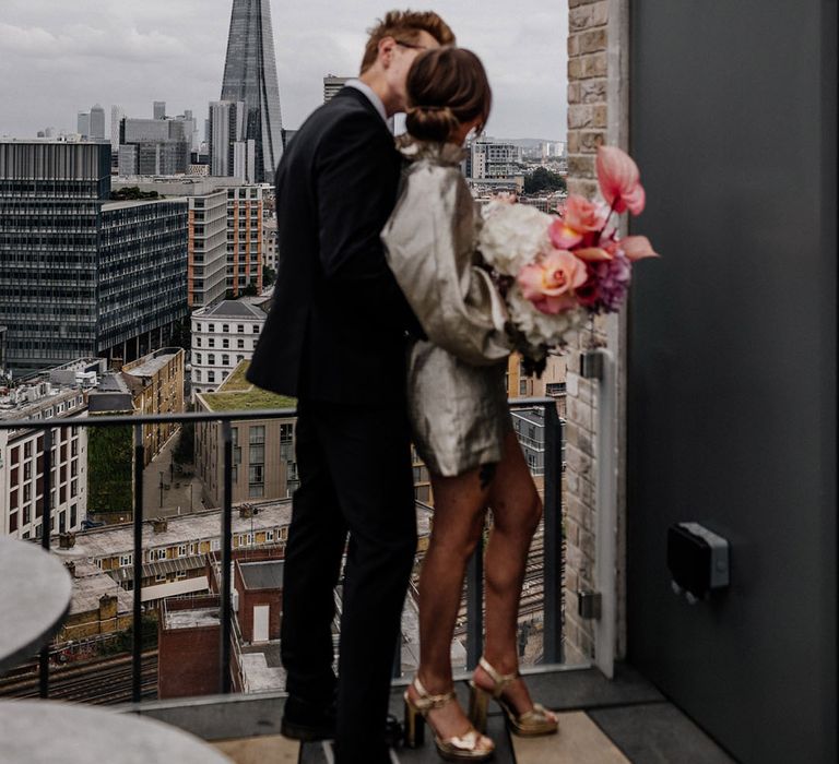 Bride in gold toned short wedding dress & heels and Groom in a dark suit, pink toned bouquet of hydrangea, cascading orchids & roses 