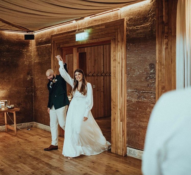 Bride & groom celebrate as they walk through door holding hands