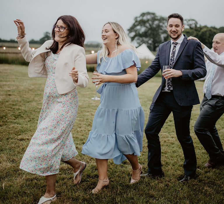 Wedding guests dance across the field at Godwick Barn