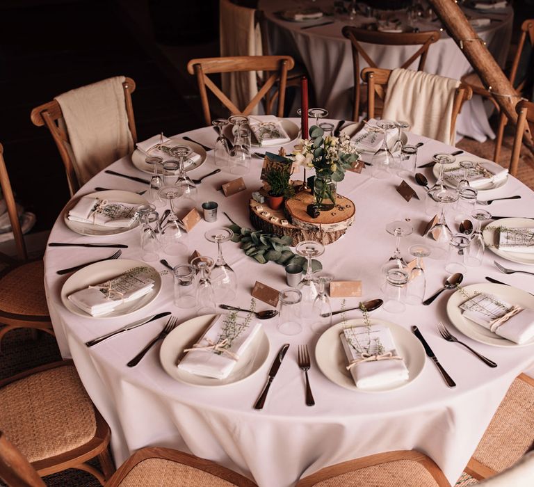 Circular rustic wedding table with wooden chairs and rustic decor