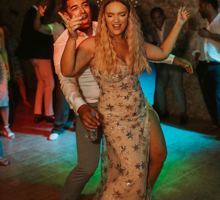 Bride dances on her wedding day outdoors in front of colourful lighting 