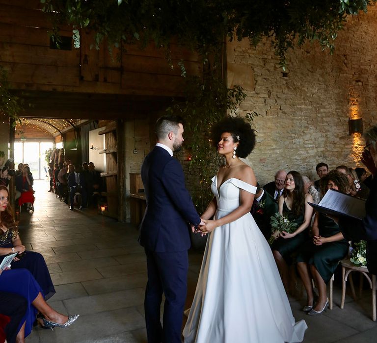 Bride & groom hold hands and look lovingly at one another during ceremony