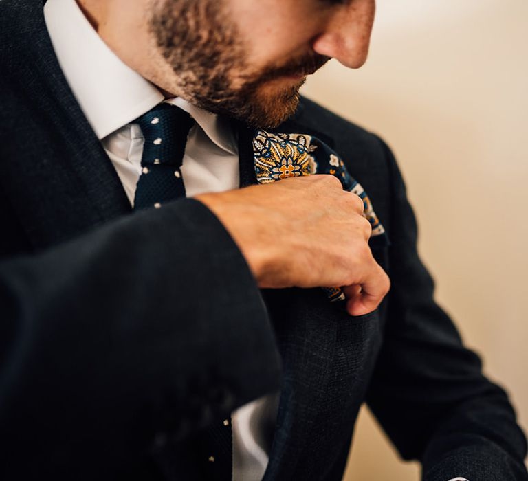 Groom does up his buttonhole on the day of his wedding