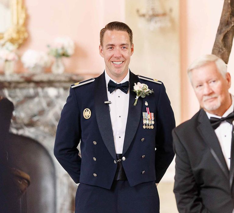 Groom waits at the end of the aisle wearing Military Uniform on his wedding day