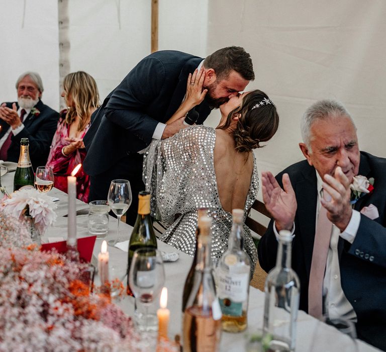 Groom kissing his bride during the marquee wedding speeches 