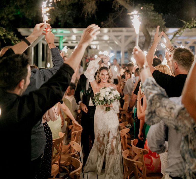 Bride & groom walk through wedding guests holding sparklers on their wedding day