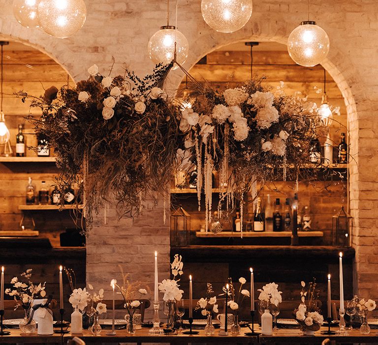 Stylish winter wedding atIscoyd Park Coachhouse with dried grass and fresh flower installation, taper candles and flowers stems in bottles 