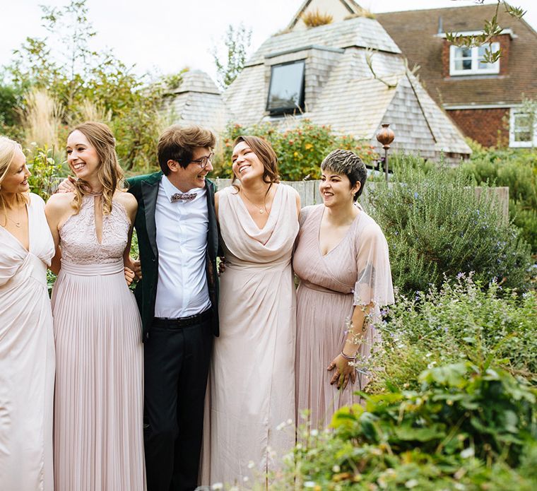 Groom in velvet tuxedo jacket with bridesmaids in varied blush pink dresses