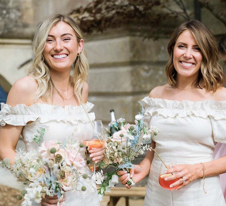 Bridesmaids with curled hair, off the shoulder puff sleeve off-white dresses and pastel pink, blue and white bouquets