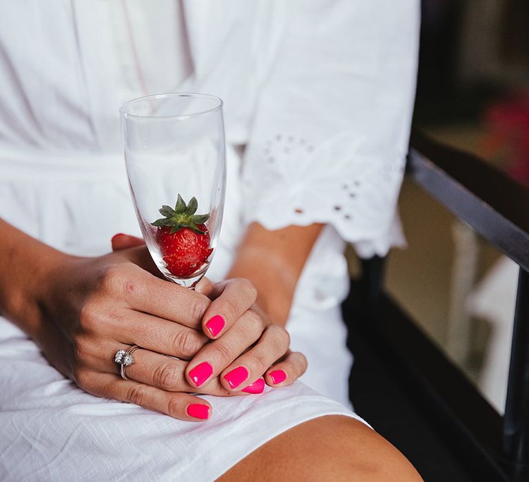 Bride has hot pink nails for her wedding with pear shape engagement ring